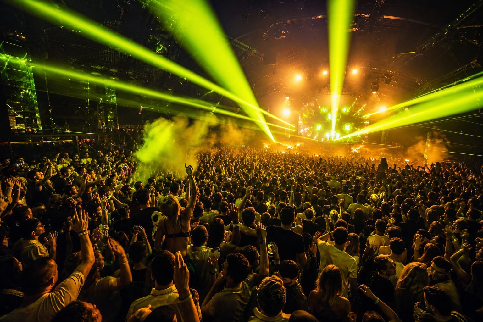 Pista lotada em show noturno, com lasers verde-limão e o público de mãos para o alto.